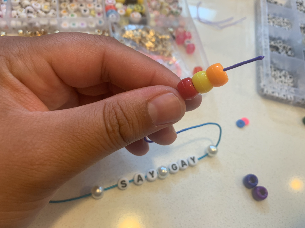 fingers holding string with pony beads on it