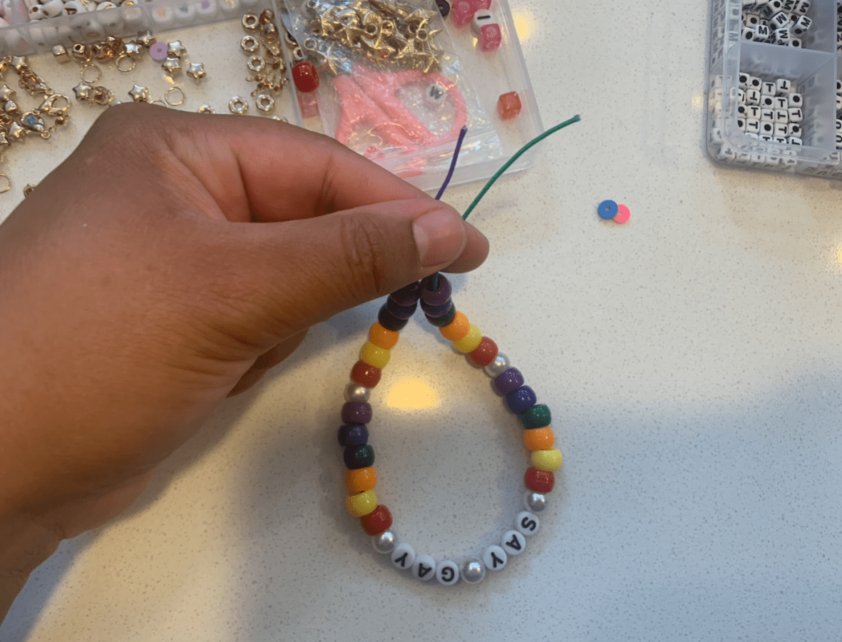 a bracelet that says SAY GAY on it with rainbow pony beads