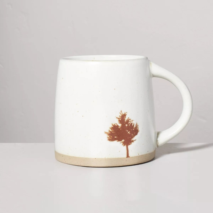 an off white ceramic mug with an orange tree on it