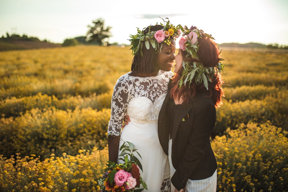 two lesbian brides kissing in a sunlit field