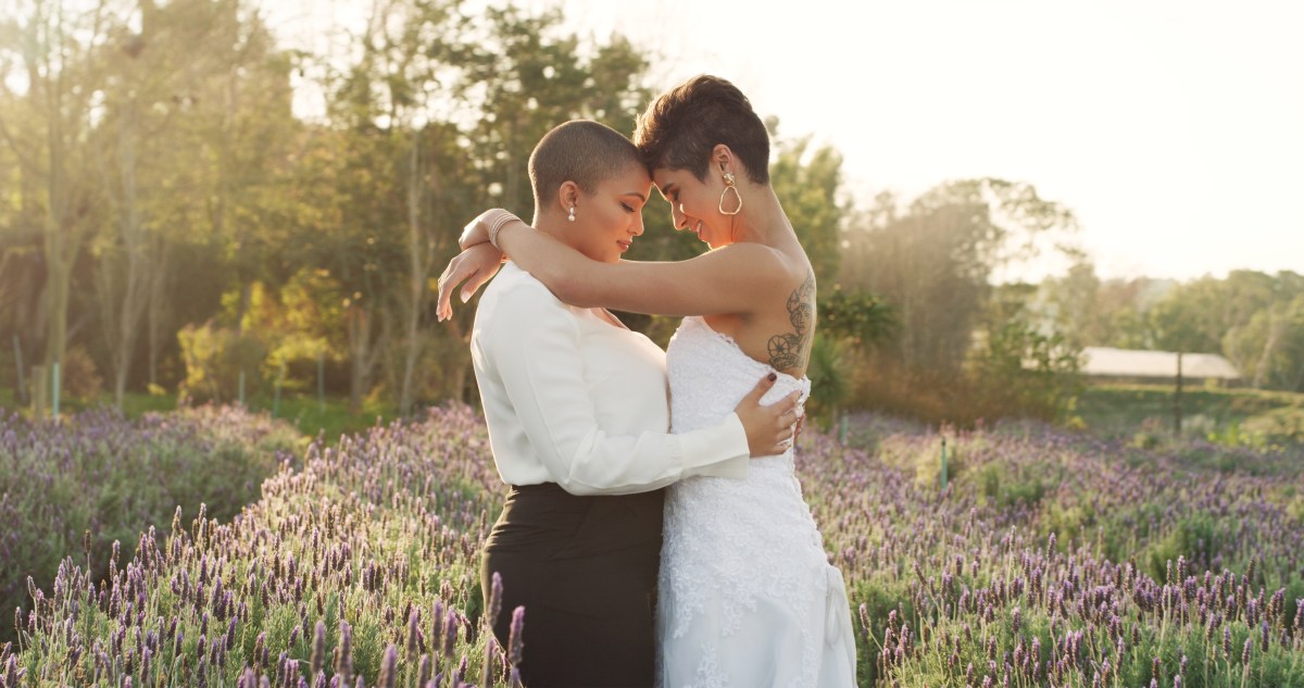 Cropped shot of an affectionate young lesbian couple  standing with their arms around each other in a meadow on their wedding day