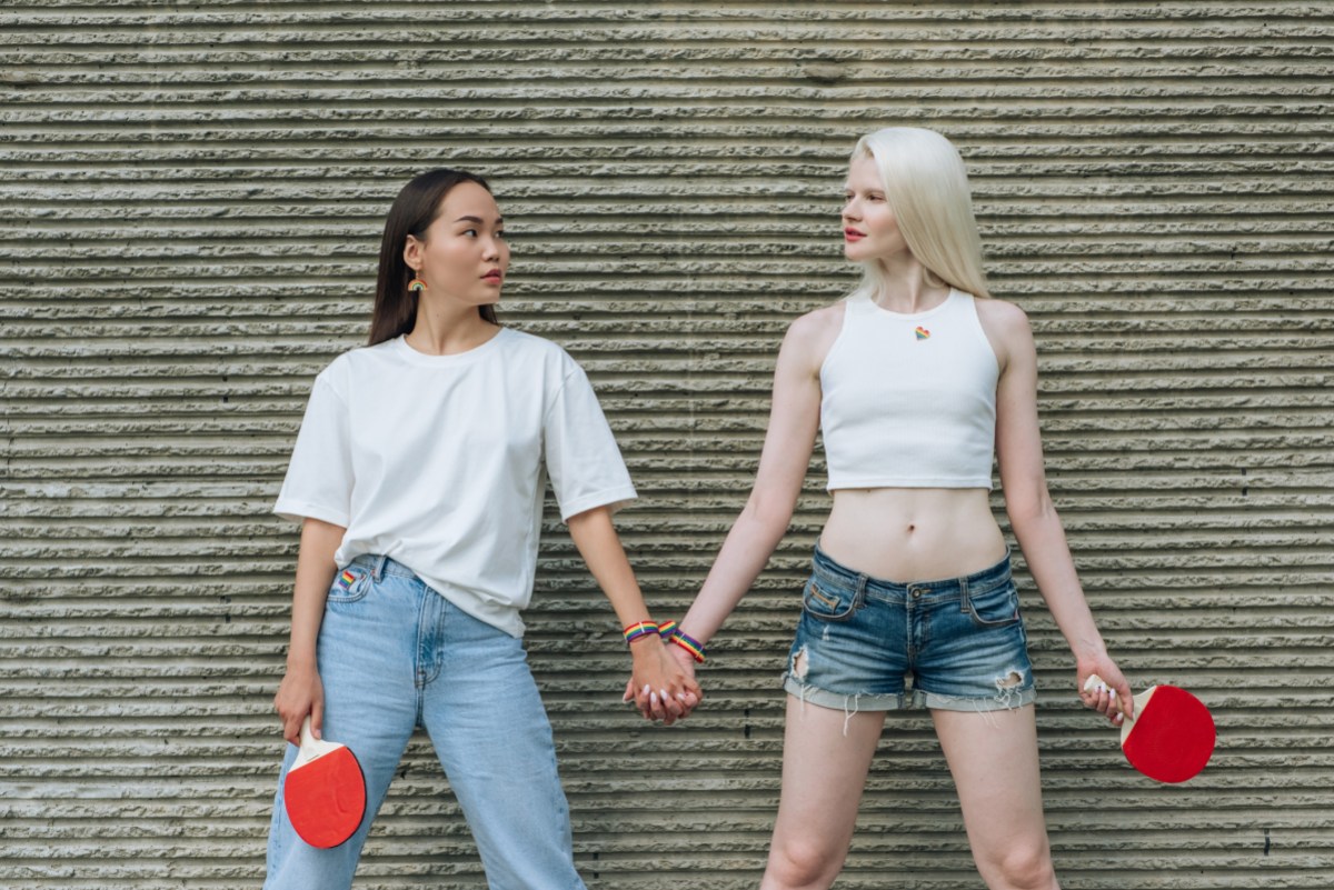 two women hold hands while holding ping pong rackets