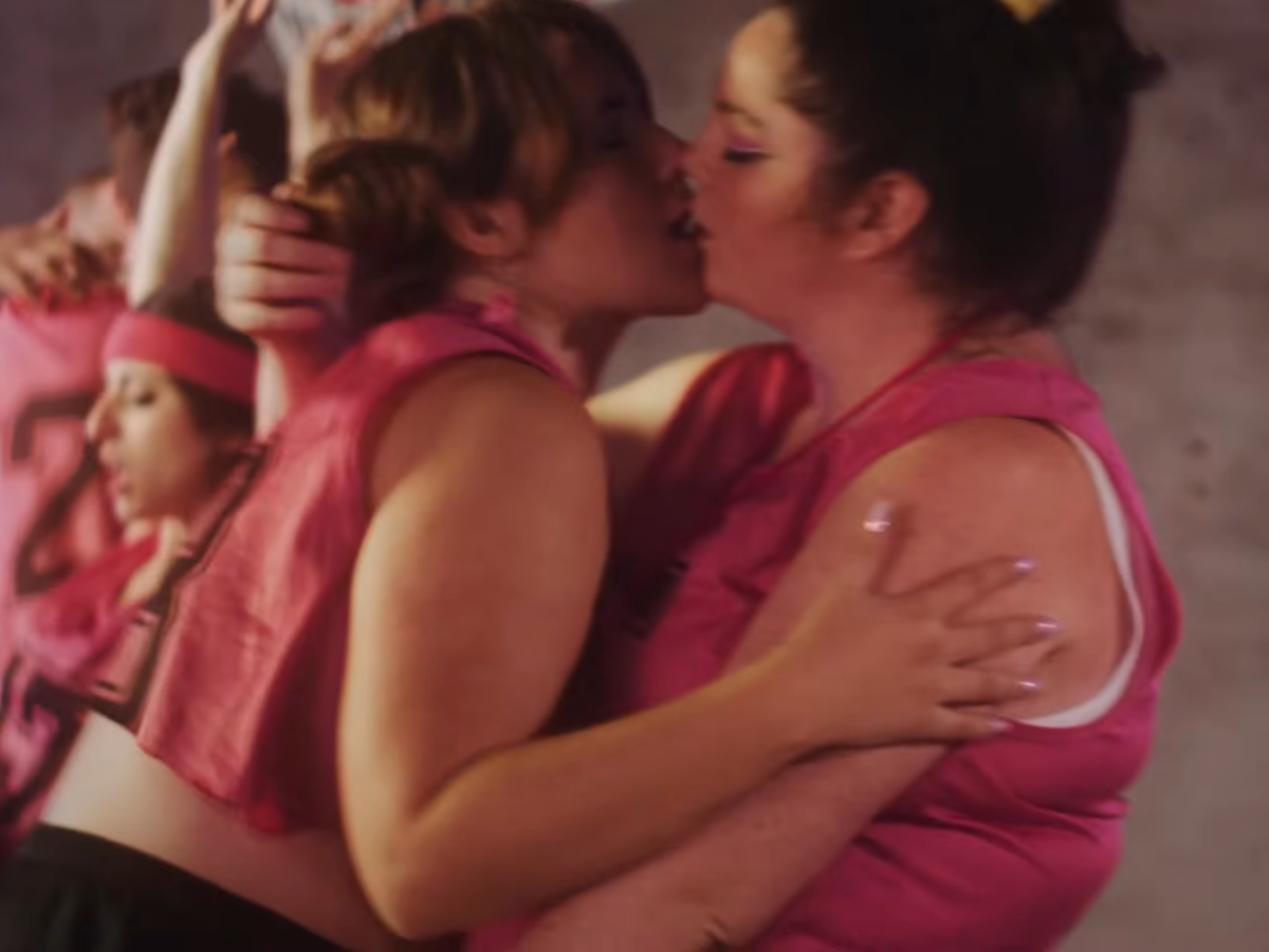 two Queerleaders in pink jerseys kiss in the Sir Babygirl "Cheerleader" music video
