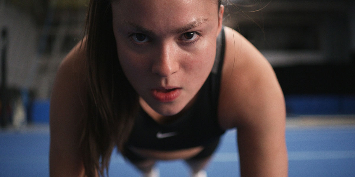 Devery Jacobs stares toward the camera mid push up.