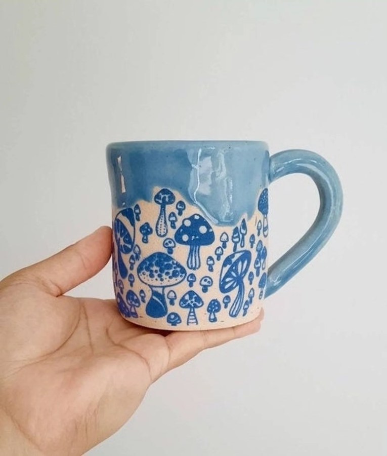 a blue and off white ceramic mug with mushrooms on it