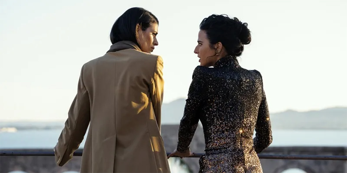 Cruz and Aaliyah engage in an intense conversation as they overlook the preparations for Aaliyah's nuptials, slated for the next day. Cruz is on the left wearing a brown pants suit, while Aaliyah is on the right, wearing a sparkly black dress.