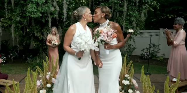 Robin Roberts and Amber Laign kiss as they walk back down the aisle after getting married