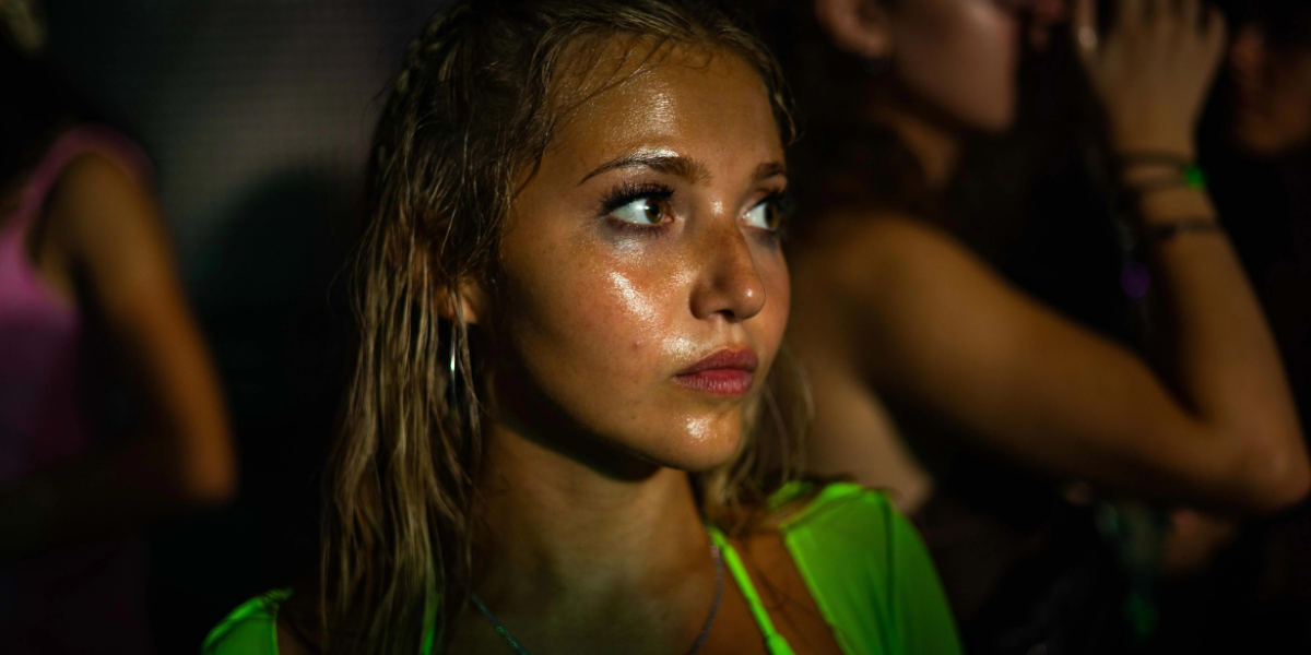 a blonde white teen girl stands in a club, covered in sweat