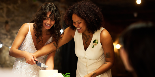 at a queer wedding, two brides cut a cake
