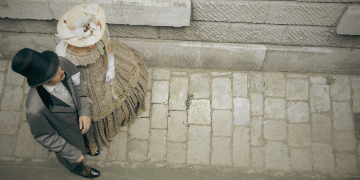 a Victorian couple walking on a cobblestone path