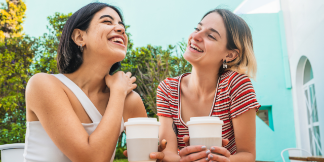 two women laughing over coffees on a first date