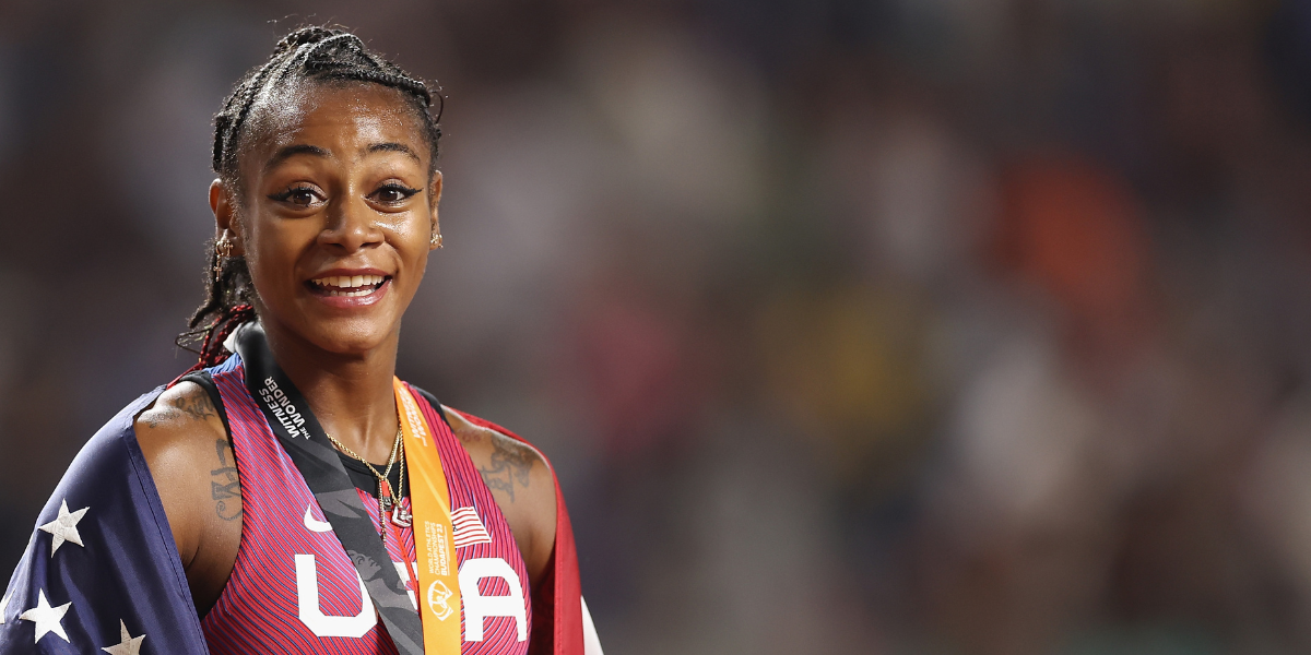 Sha'Carri Richardson wearing a USA uniform, flag, and medal at a recent race