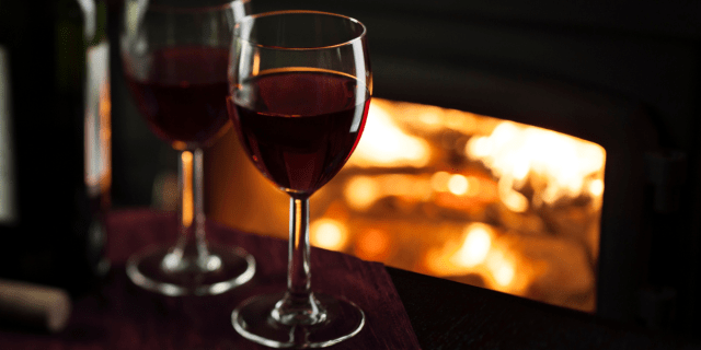 a glass of chilled red wine by a hearth