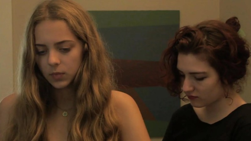 Queer horror to stream: the short films of Jennifer Reeder. Two girls — one blonde, one brunette — look down solemnly.