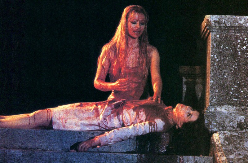 a woman covered in blood standing over another woman covered in blood