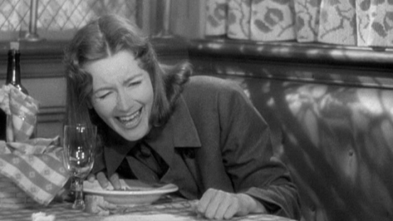 Ninotchka laughs at a dining table