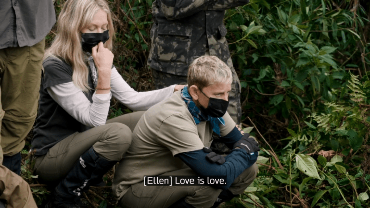 Ellen and Portia crouch down near the gorillas wearing masks. CC: [Ellen] Love is love.