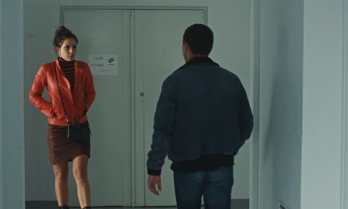 Clothes from Passages: Adèle Exarchopolous wearing a black and red turtleneck, a black jacket, and a mini-skirt is in a hallway talking to a man. 