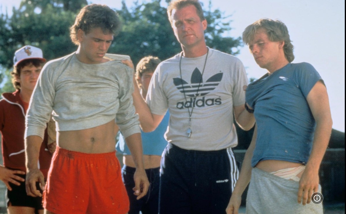 coach holding two teenage boys by the scruff of their shirts