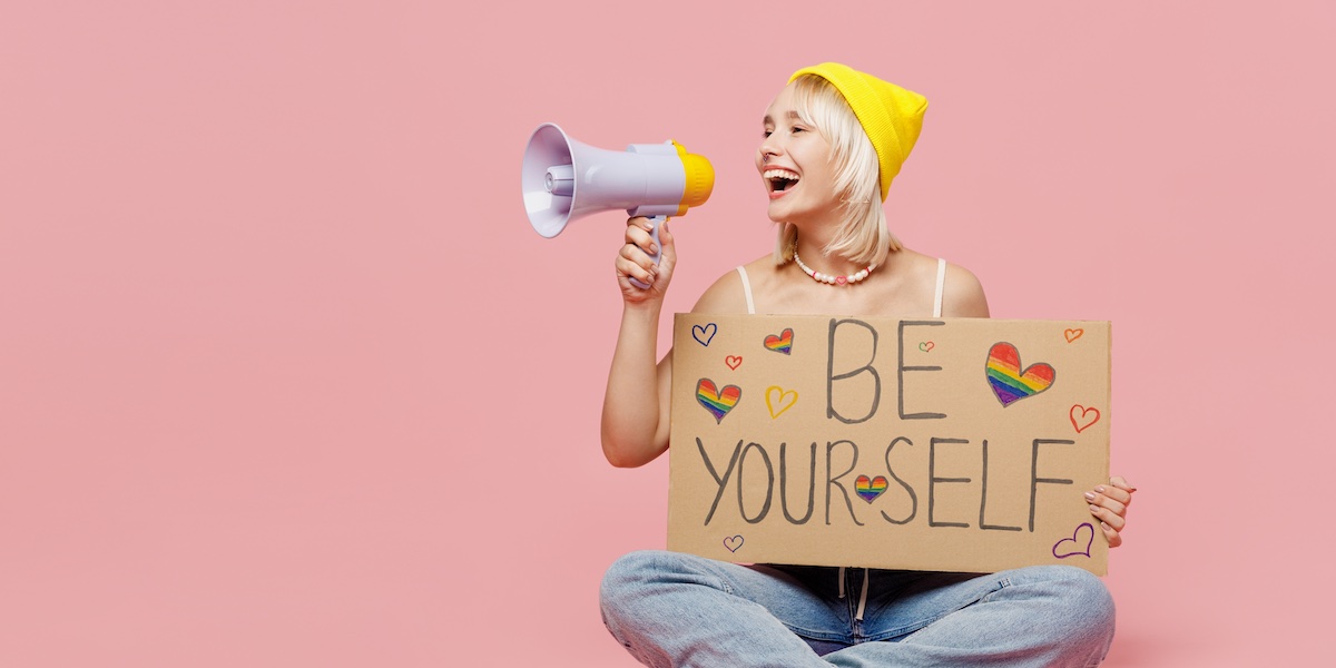 girl in a yellow hat holding sign that says "be yourself"