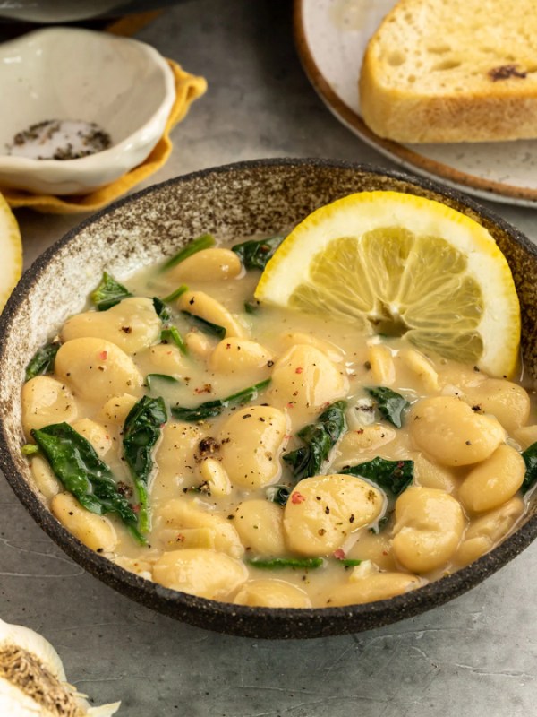 a bowl of large butter beans with spinach, lemon, and garlic