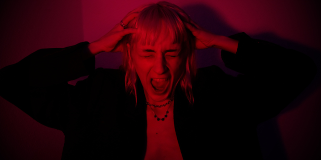 a woman screaming with her hands on her head