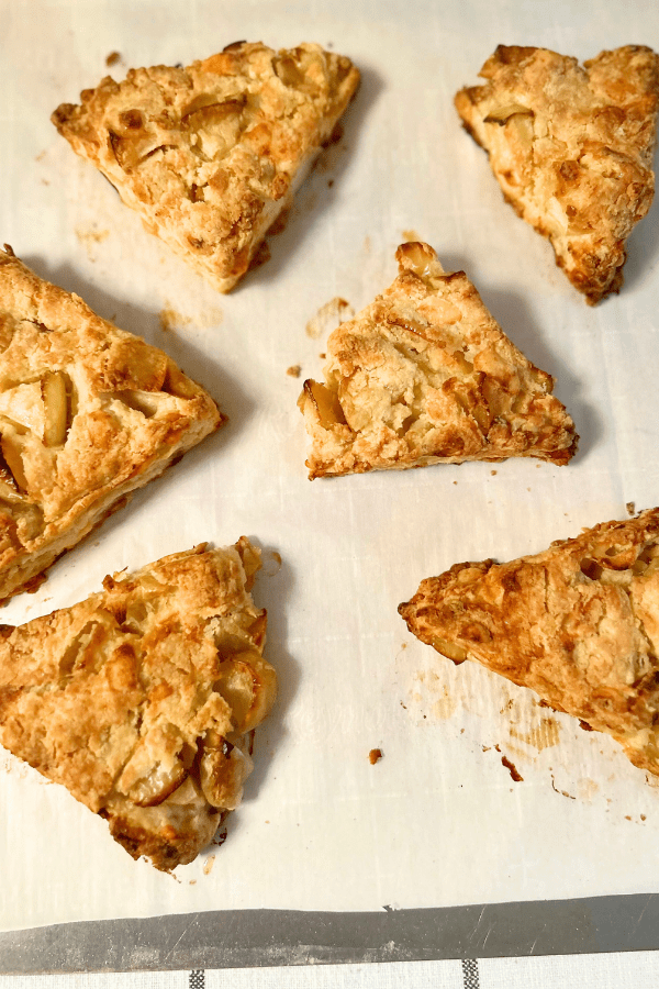 Apple cheddar scones, piled together on top of parchment paper