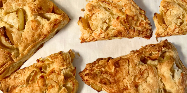 Apple cheddar scones, piled together on top of parchment paper