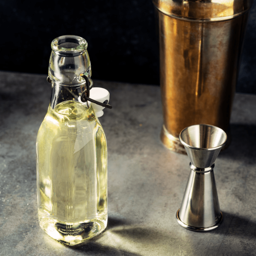 a photo of a simple syrup in a bottle with a shot glass and shaker