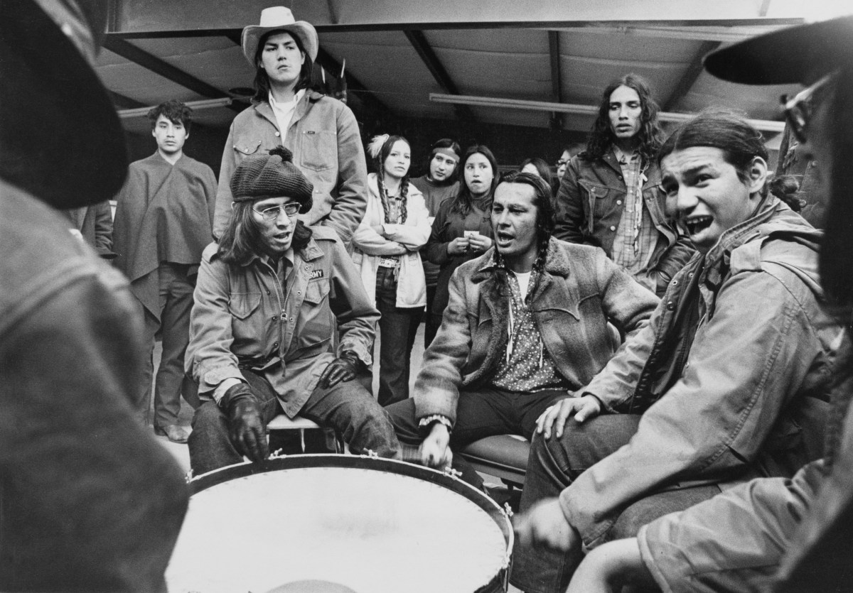 Members of the American Indian Movement (AIM) chant and beat a drum to serenade those who will man the outposts during the Wounded Knee Occupation (also known as Second Wounded Knee) at Wounded Knee on the Pine Ridge Reservation, South Dakota, 23rd March 1973