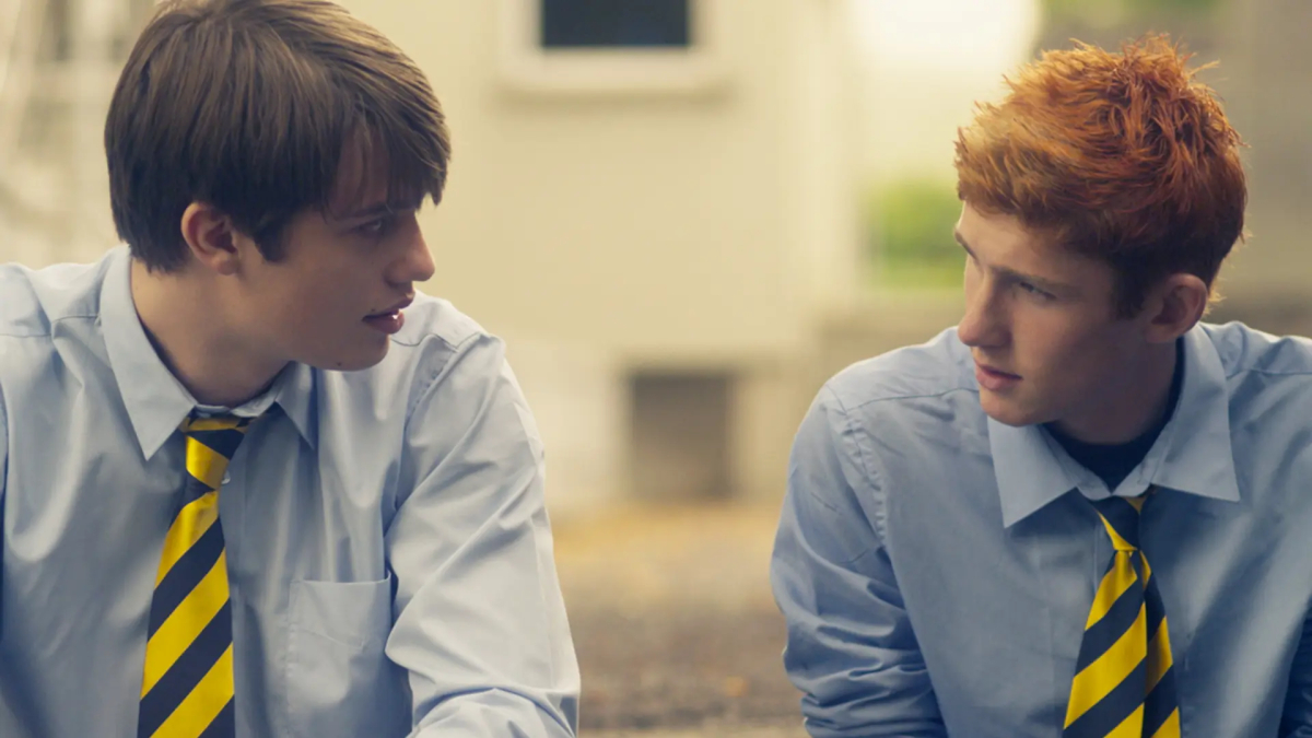 Queer Sports Movies: Nicholas Galitzine and Finn O'Shea sit next to each other wearing matching button down shirts and striped ties in Handsome Devil.