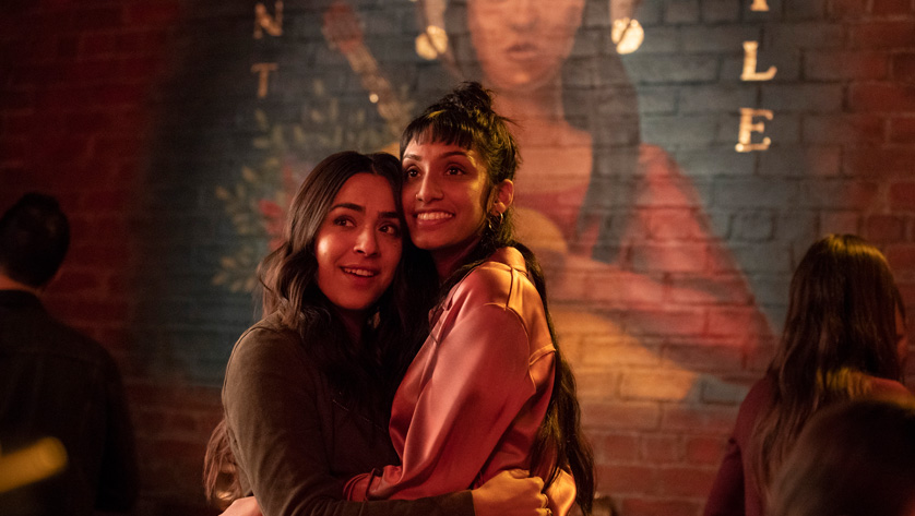 two women hug each other in a basement bar