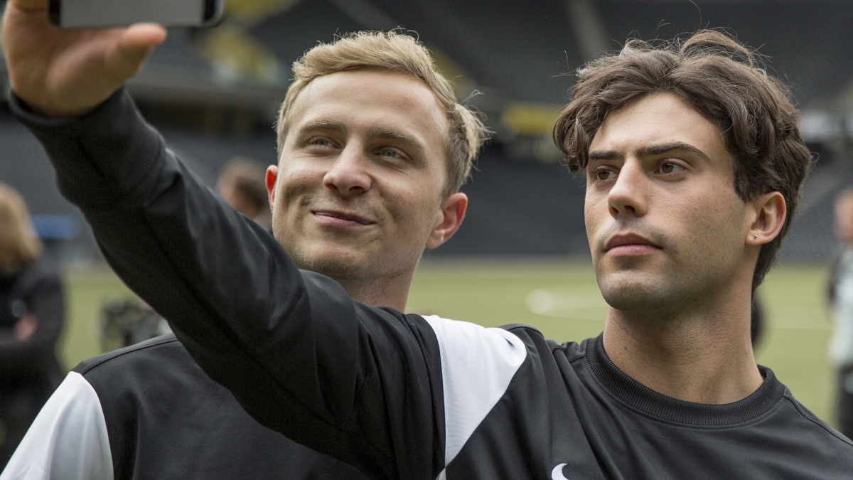 Queer sports movies: two male soccer players take a selfie on the pitch