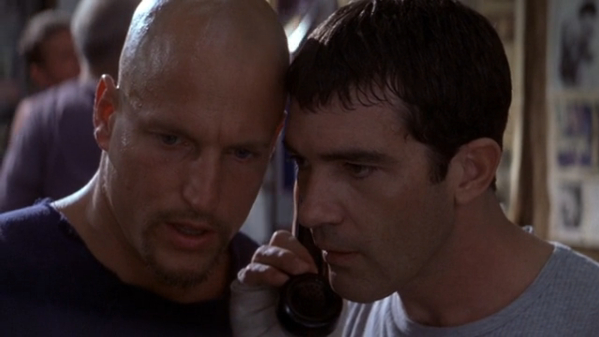 Woody Harrelson and Antonio Banderas listen to a phone at a boxing gym in Play it to the Bone.