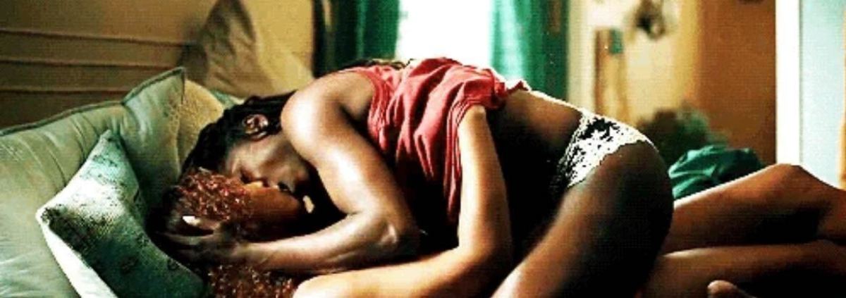 Sexy lesbian screenshot: Rutina Wesley straddles another woman as they kiss in a wide shot.