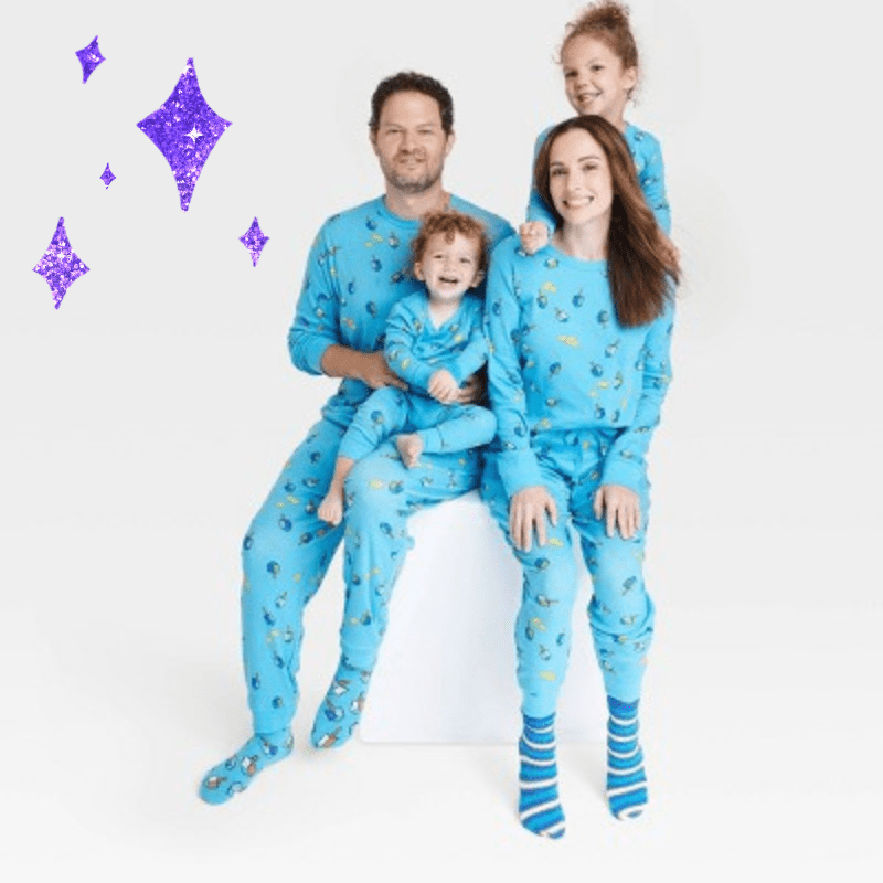two parents and two toddles in matching blue pajama sets with dreidels on them