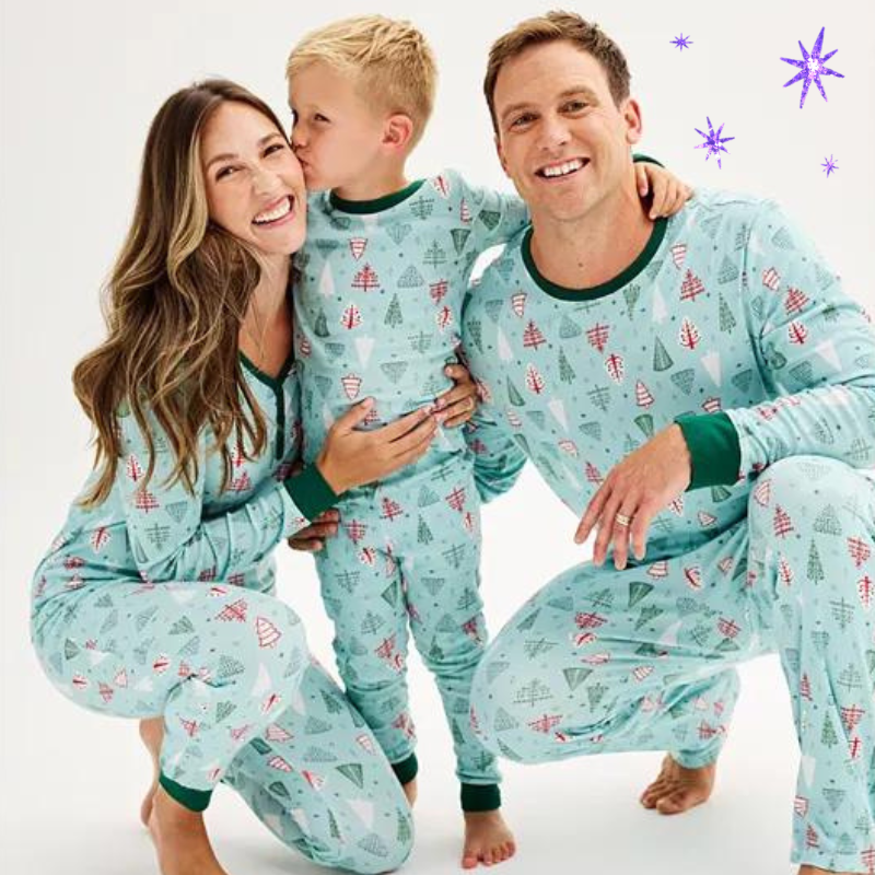 two parents and a toddler wearing matching christmas tree pajama sets