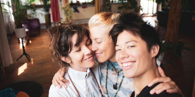 three queer women holding each other