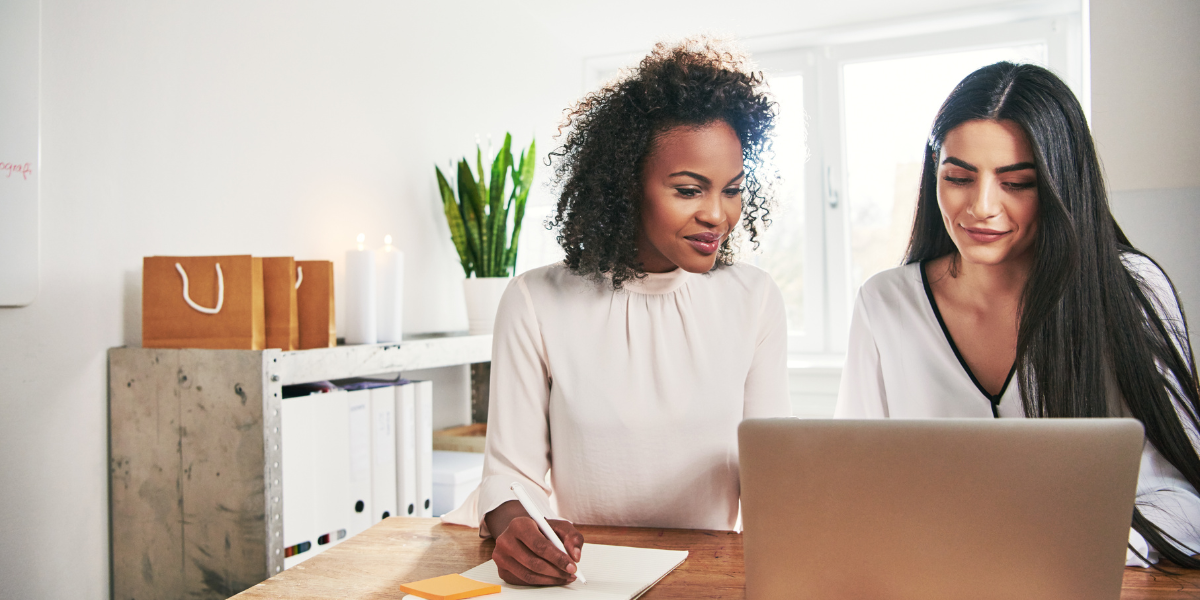 two women working together, looking at a laptop