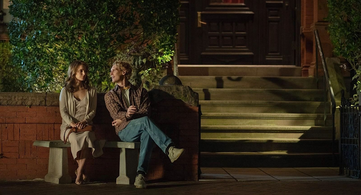 Natalie Portman sits next to Cory Michael Smith outside a restaurant.
