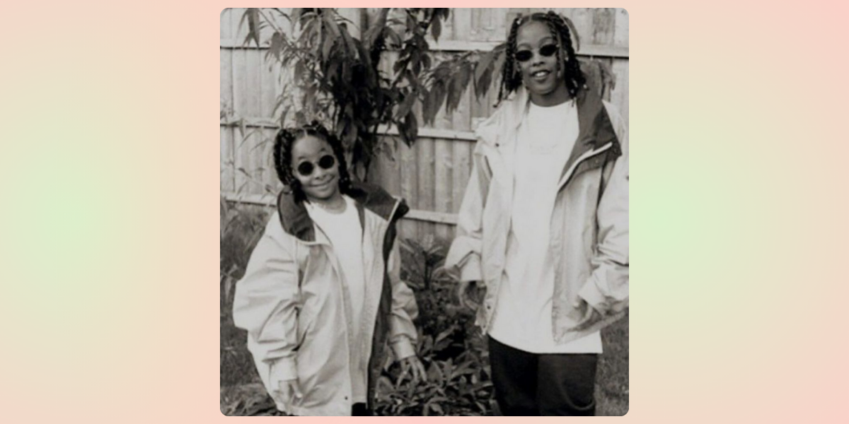 Raven-Symone and Da Brat as children in black and white standing in a yard wearing sunglasses and big jackets