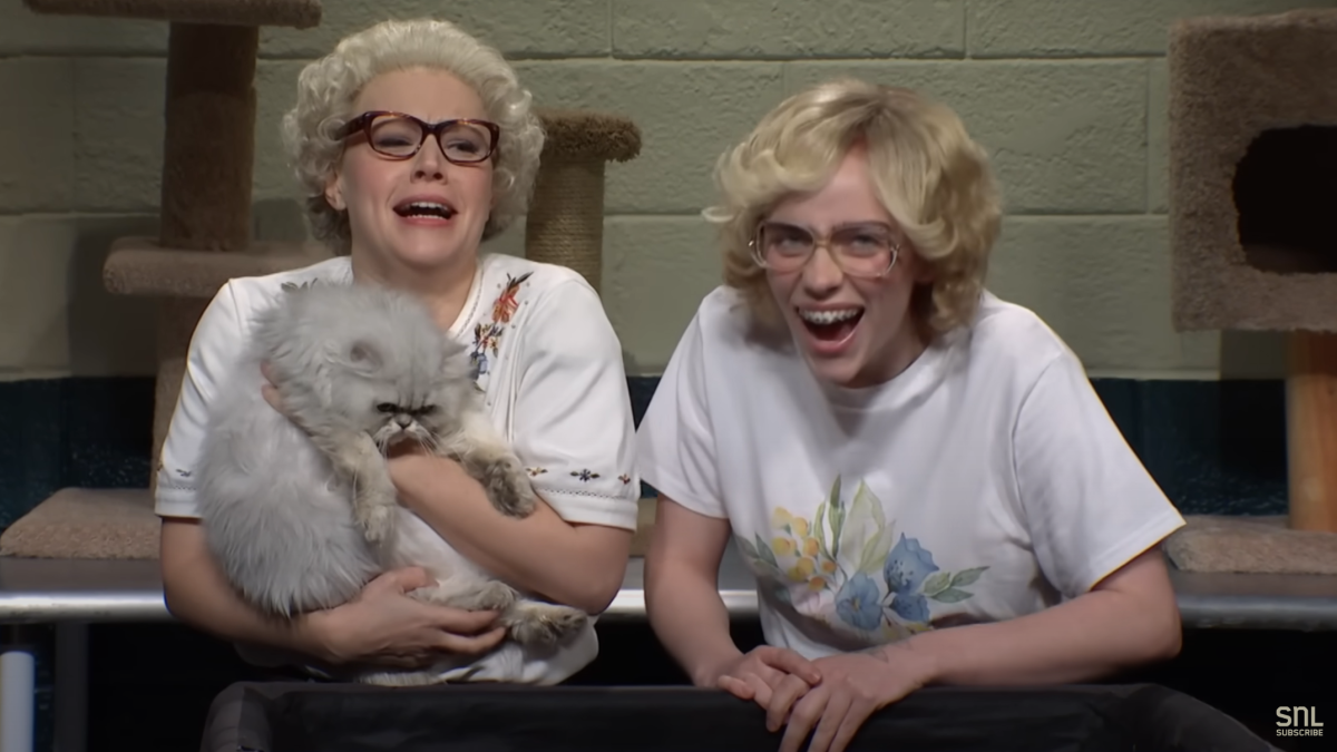 Kate McKinnon and Billie Eilish holding a cat and laughing in the Whiskers R We sketch