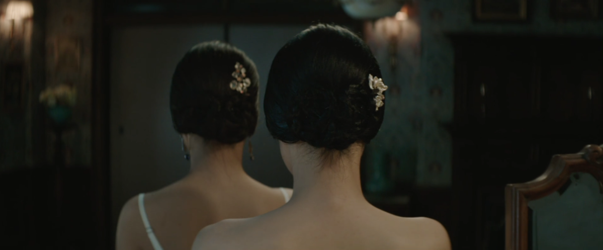 Hideko and Sook-hee from behind, with matching intricate bun hairstyles