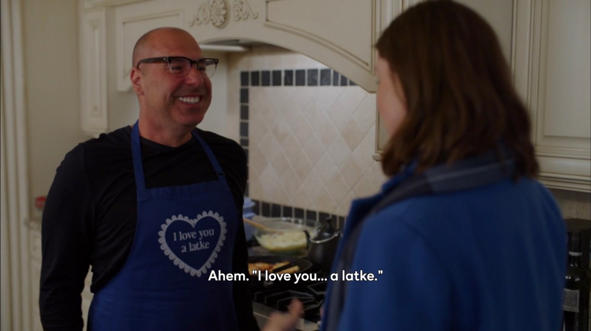 dad smiling in an apron that says "i love you a latke"