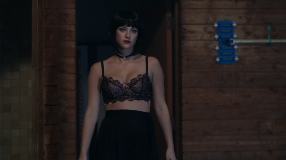 Betty in a black bob wig and a bra.