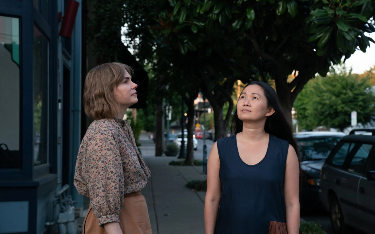 Michelle Williams and Hong Chau stand next to each other looking up to the sky.