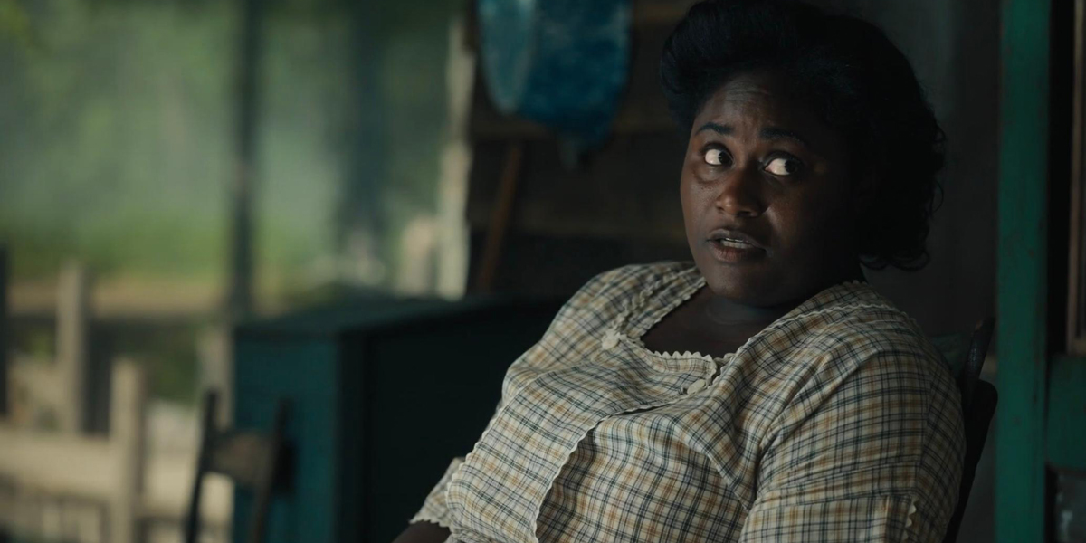 Danielle Brooks as Sophia, sitting on the porch, in the color purple