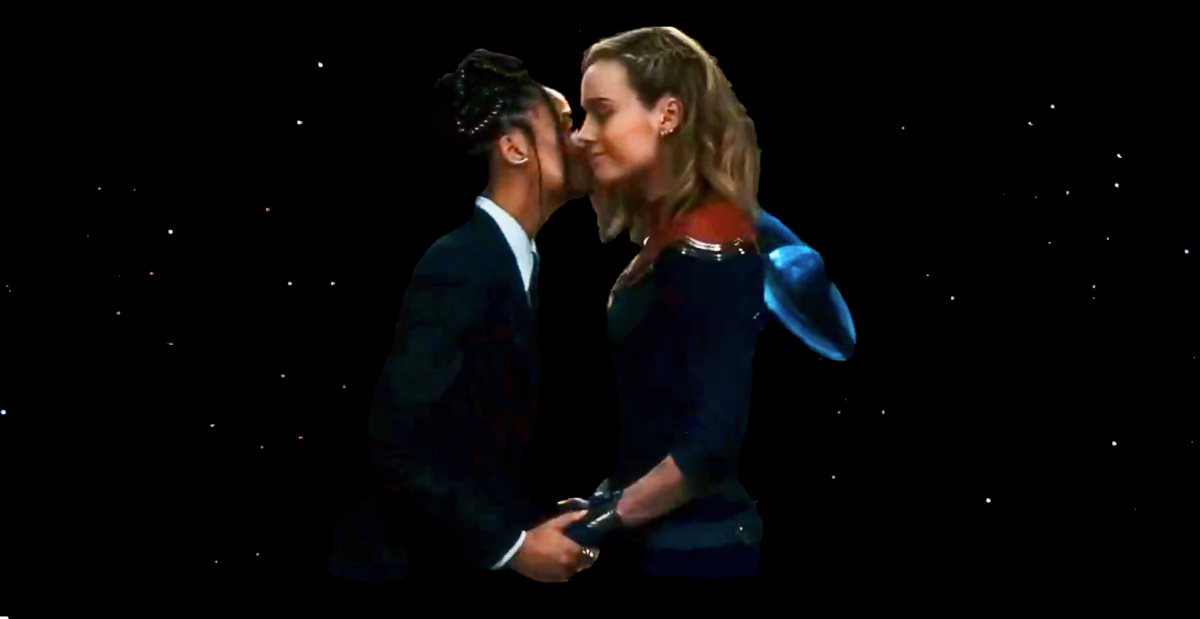 Tessa Thompson kisses Brie Larson on the cheek in front of a black background.