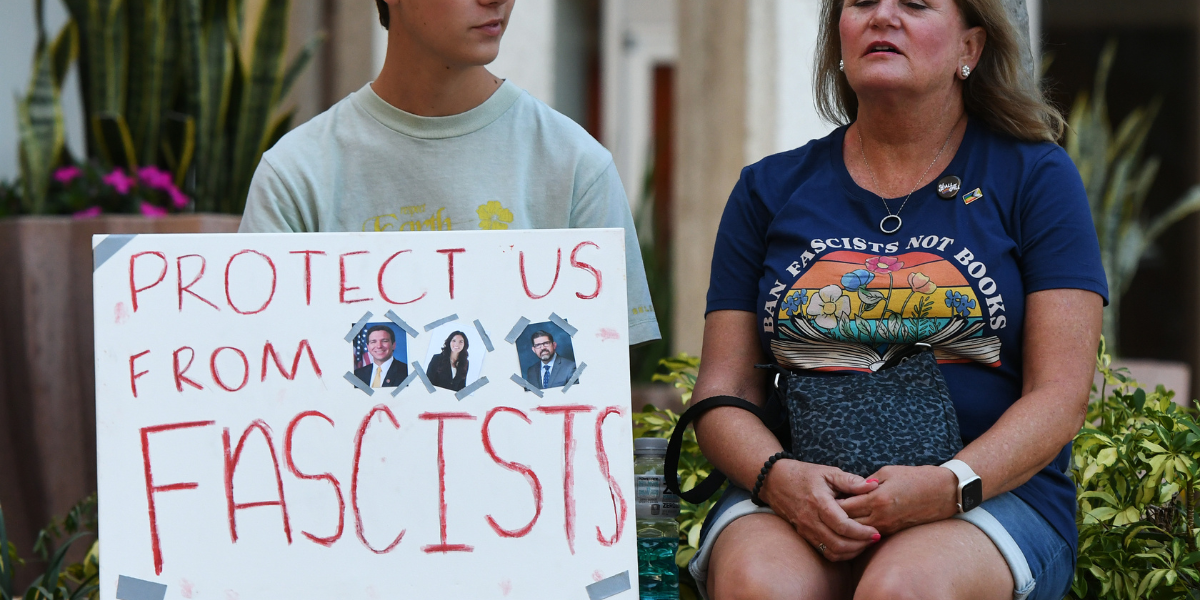 a student holds a sign that says PROTECT US FROM FASCISTS