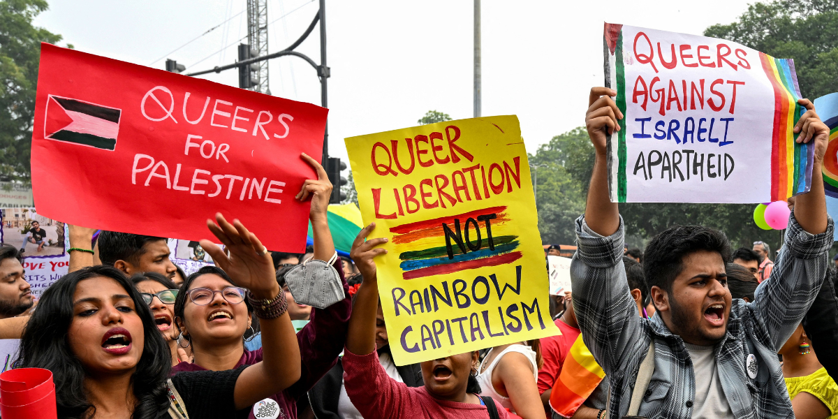 a group of queer protesters hold signs that read QUEERS FOR PALESTINE, QUEER LIBERATION NOT RAINBOW CAPITALISM, and QUEERS AGAINST ISRAELI APARTHEID